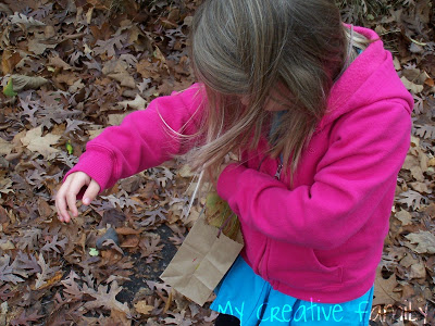 Young girl with a small brown paper bag she is using to collect fall leaves.